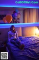 A woman sitting on a bed with balloons in the background.