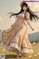 A woman in a long dress and hat standing in a field.