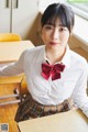 A woman in a school uniform sitting at a desk.