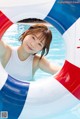 A young girl in a swimming pool with a life preserver.