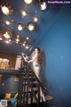 A woman in a fishnet dress is standing on the stairs.