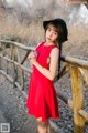 A woman in a red dress and black hat posing for a picture.