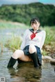 A woman in a school uniform sitting in the water.