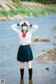 A woman in a school uniform standing in the water.