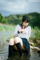 A woman in a school uniform sitting in the water.