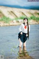 A woman in a school uniform standing in the water.