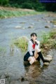 A woman sitting on a rock in a river.