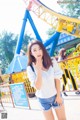 A young woman standing in front of a roller coaster.