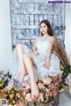 A woman sitting on a chair surrounded by flowers.