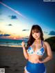 A woman in a blue bikini standing on a beach.