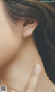 A close up of a woman's neck with her hand on her neck.