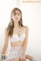 A woman in a white lingerie sitting on a chair.