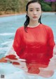 A woman in a red dress standing in a pool.