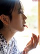 A woman in a kimono applying lipstick to her lips.