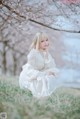 A woman in a white dress sitting in the grass.