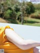 A woman in a yellow dress laying on a white bench.