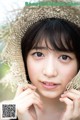 A woman wearing a straw hat is posing for a picture.