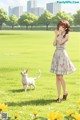 A girl in a white dress standing in a field with a white dog.