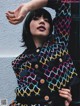 A woman in a colorful jacket leaning against a wall.